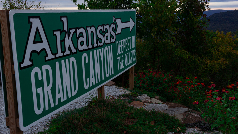 A green and white sign pointing to the Arkansas Grand Canyon