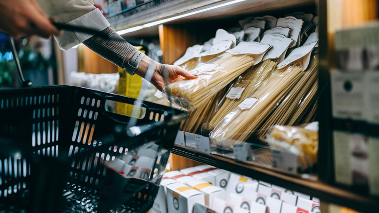 Person grabbing something off a grocery store shelf