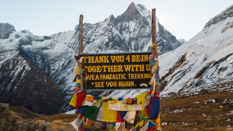 The farewell sign at the exit of the Annpurna Base Camp trail, set against the backdrop of the Himalayas in Nepal