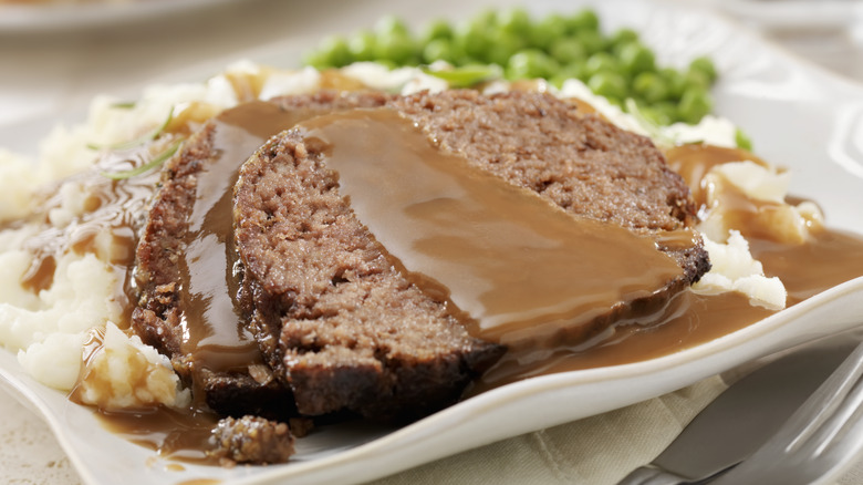 A plate of meatloaf with gravy and mashed potatoes