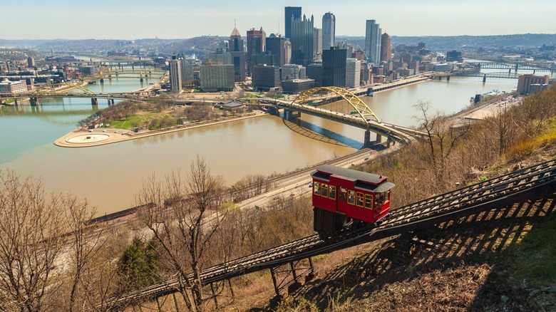 Red cable car climbs hill above downtown Pittsburgh