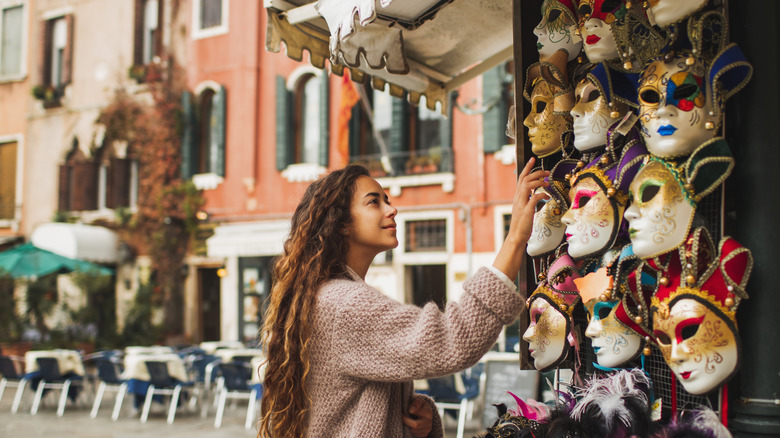 A traveler in Venice, Italy, shops for Carnival masks