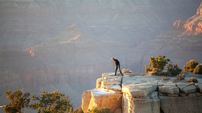 Man peering over edge Grand Canyon