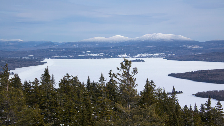 A panoramic view of an ice-covered lake with snow-covered mountains in the distance