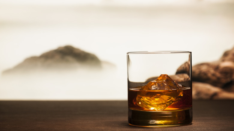 Glass of whiskey on table with misty mountain in background