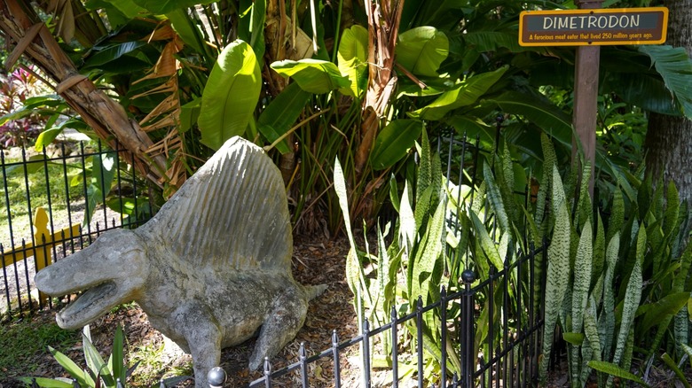 Small dimetrodon statue in the greenery of the Sugar Mill Gardens