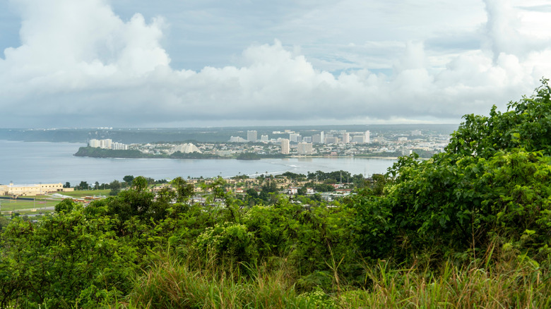 Guam's lush landscape with buildings and water in the background