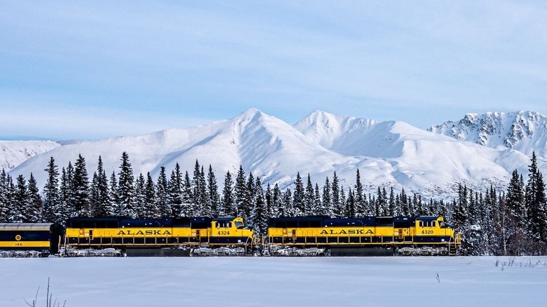 A yellow train under mountains