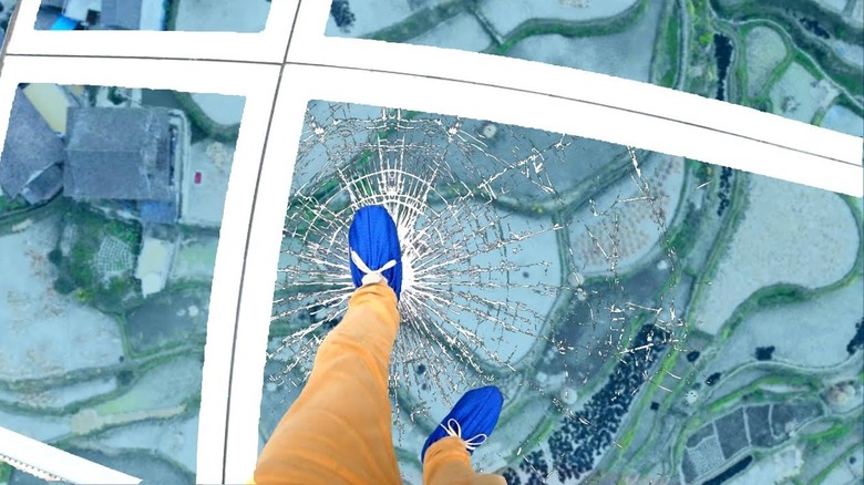 Foot steps on glass skywalk to create breaking effect