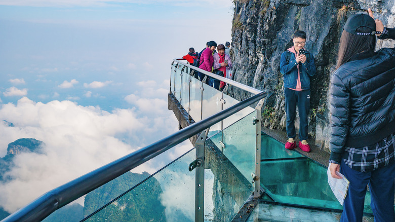 tourists take photos on cliffside glasswalk