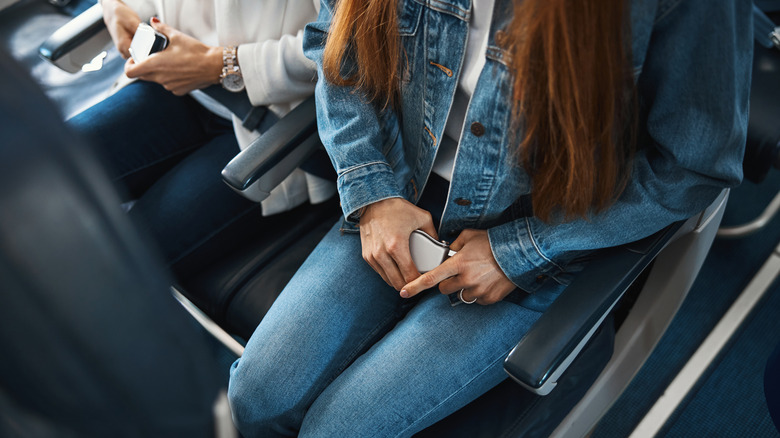 People buckling seat belts on a plane