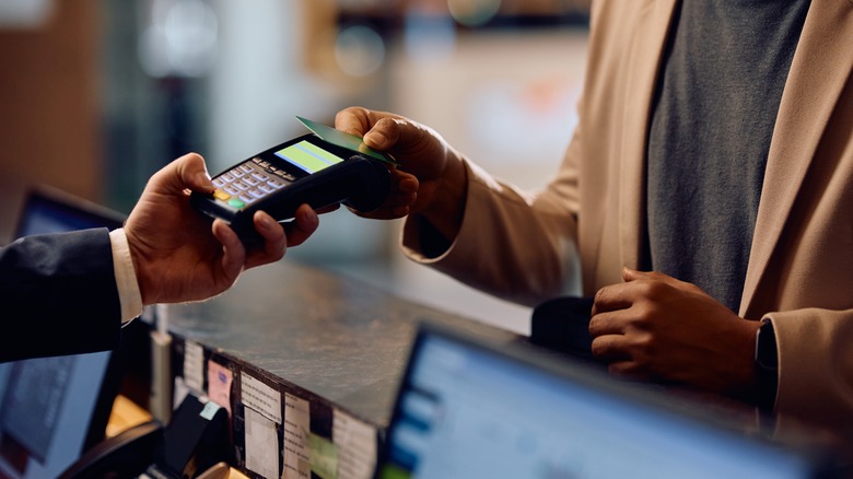 Man paying with a card at a hotel desk.