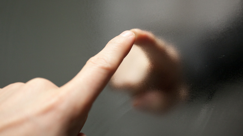 Person touching a steamy mirror with their finger.