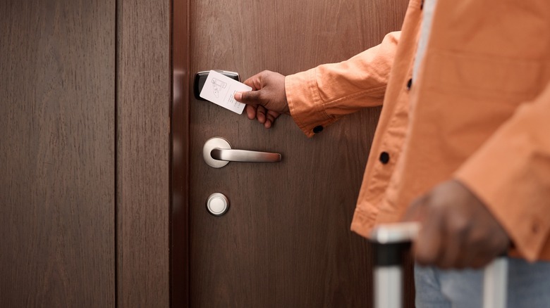 A man entering a hotel room with a key card.