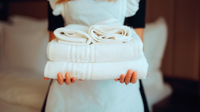 A maid holding a pile of towels.