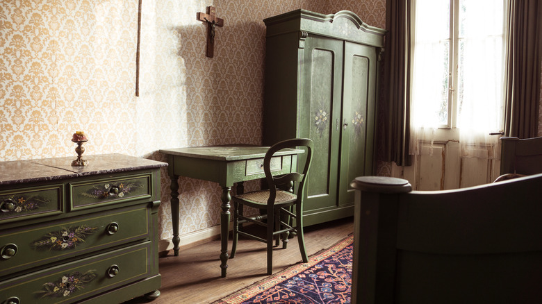 An old-fashioned hotel room with green wooden furniture.