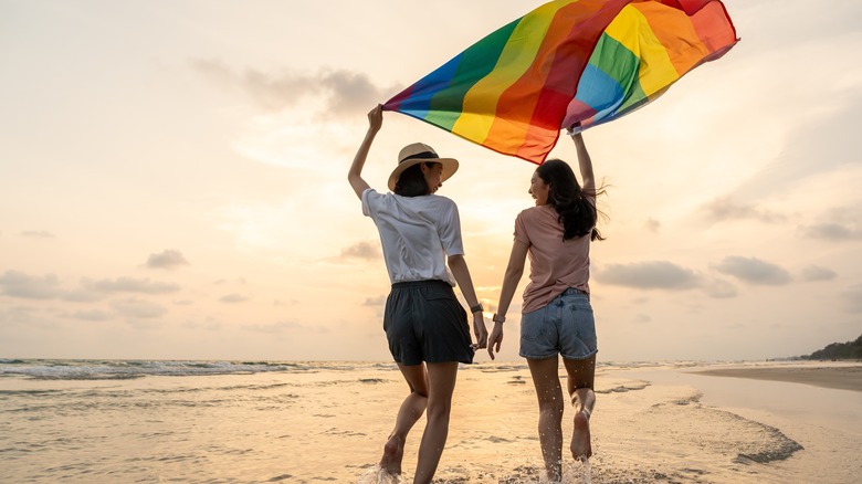 Two women on beach with a rainbow flag