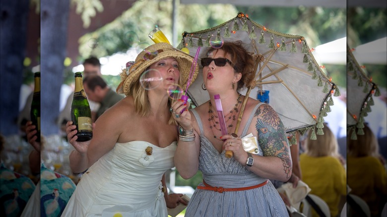 Two women blowing bubbles outside