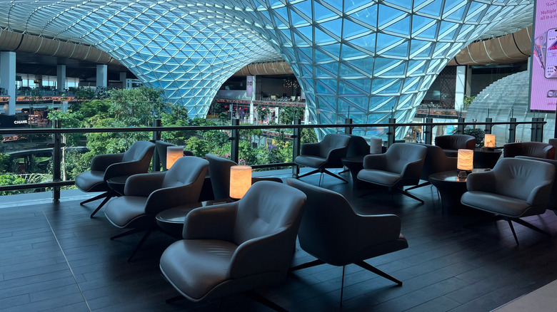 A glass of champagne and a passport on a table in a business lounge zone in an airport.