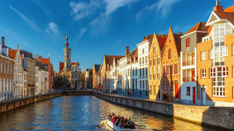 Boat going down Bruges canal with houses