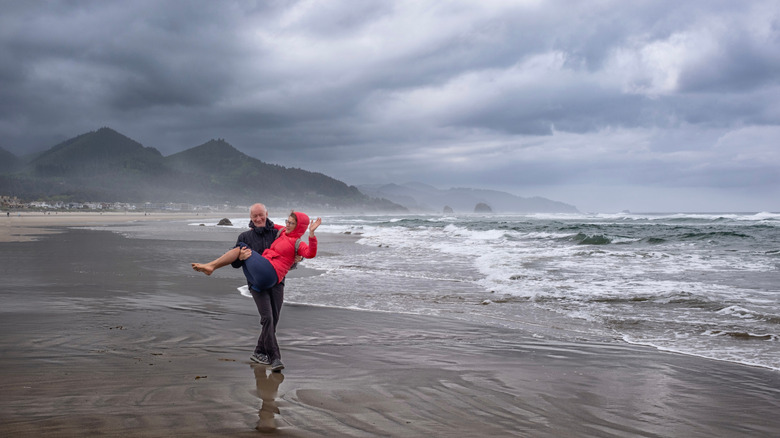 Man carries woman on beach