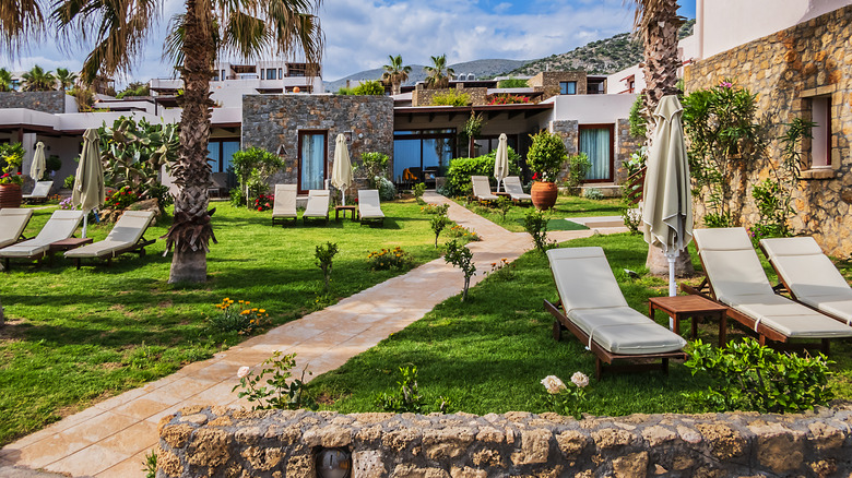 Sunbeds on the grass and local Cretan architecture at Ikaros Beach Resort in Crete