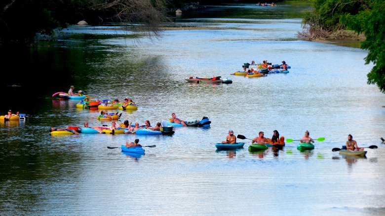 Several groups of people tubing and kayaking down the Iowa River towards Rock-n-Row Campground