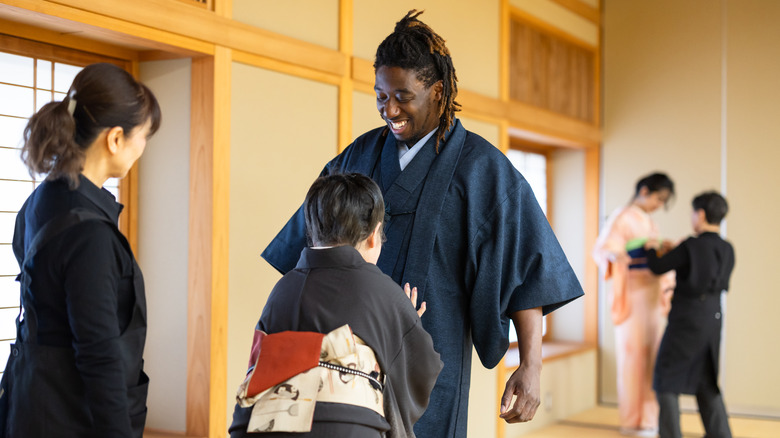 Japanese woman tying kimono on a Black man