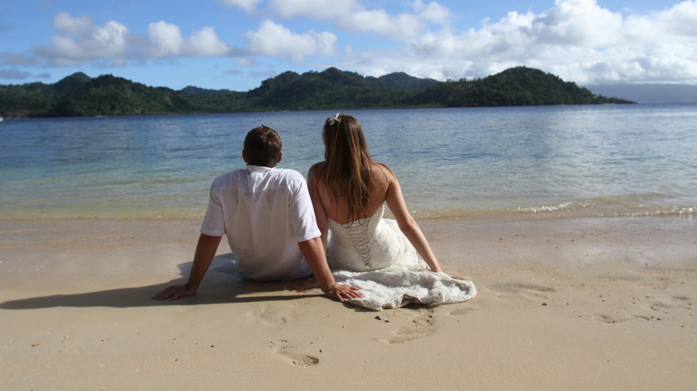 Newlyweds sit on Fiji beach
