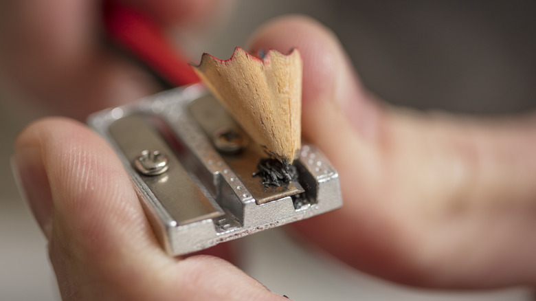 Person using hand-operated pencil sharpener