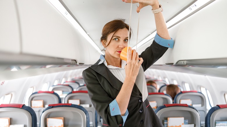 Flight attendant demonstrating the oxygen masks