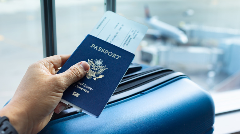 Passenger holding passport with luggage at airport