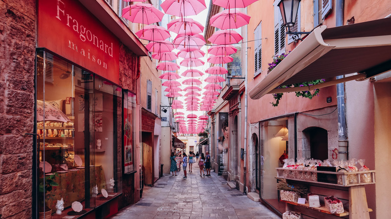 Pink umbrellas hanging over a cobbled street in Grasse