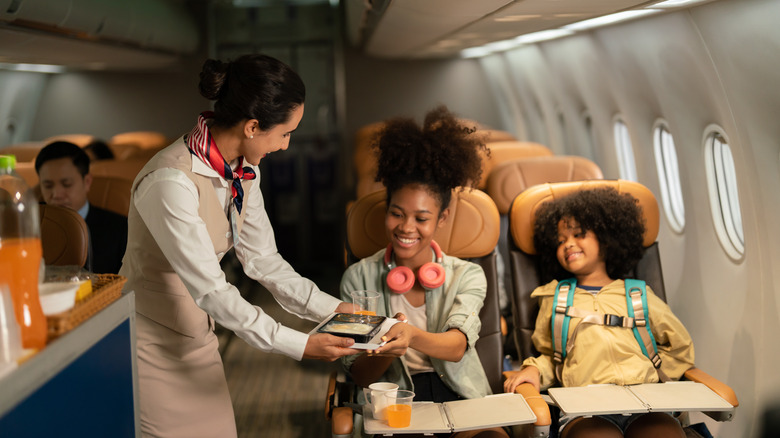 Flight attendant serving food to young passengers