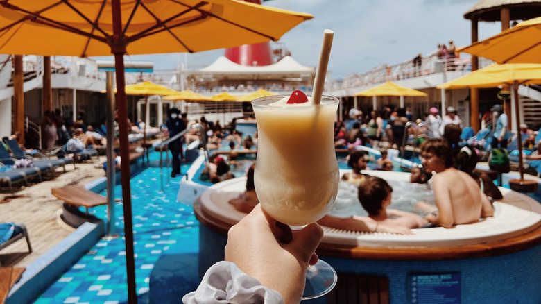 Hand holding a frozen drink on a cruise pool deck