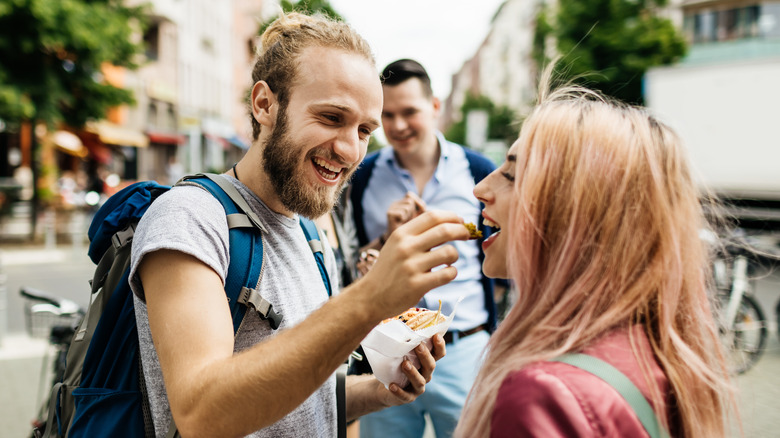 Traveling friends sharing food outside