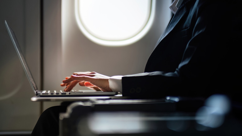 Woman working on laptop in plane