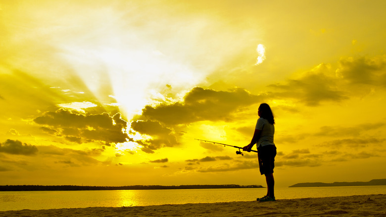 Woman fishing in Mississippi against a yellow sky