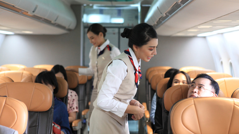 Flight attendants helping passengers