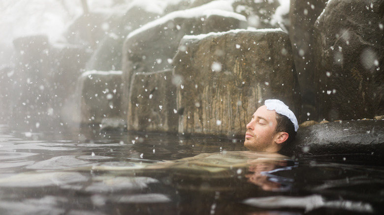 Man submerged in snowy hot spring pool