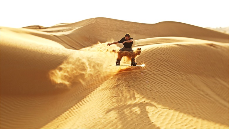 A man sandboarding on a dune