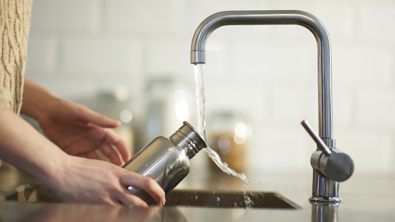 Woman filling metal water bottle