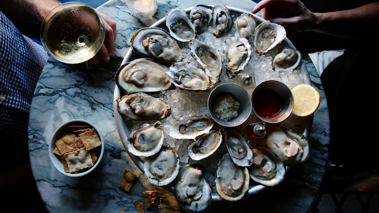 Raw oysters on the half shell over ice served at a table