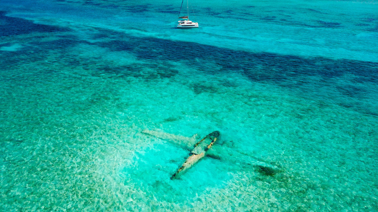 Plane wreck snorkeling site and anchored sailboat, Norman's Cay, Bahamas