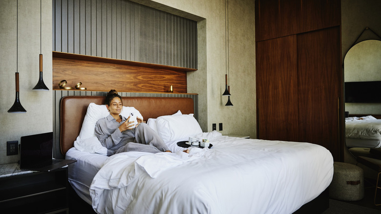 A person relaxing in their hotel room in bed