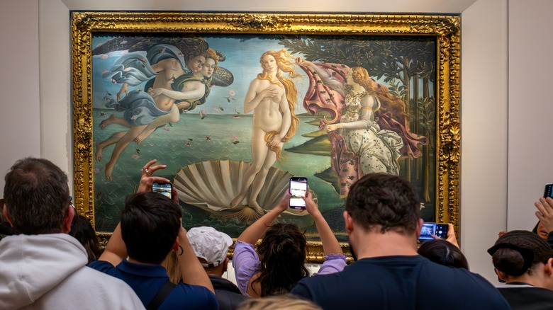 People taking pictures of the "Birth of Venus" painting in a gallery