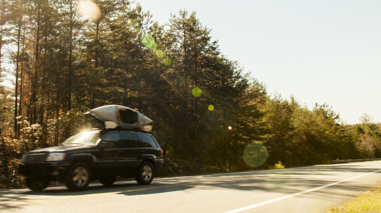 Car driving down road with kayaks on roof