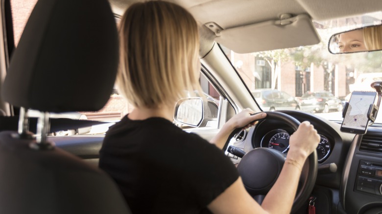 Woman driving with hands positioned on the steering wheel