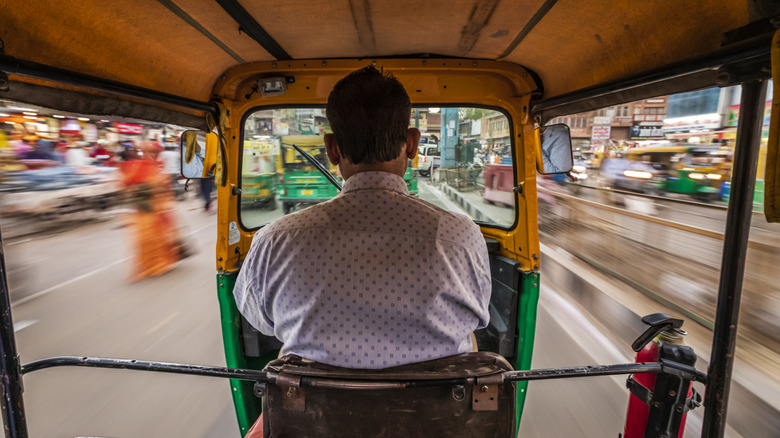 A tuk-tuk driver speeding through the streets of India