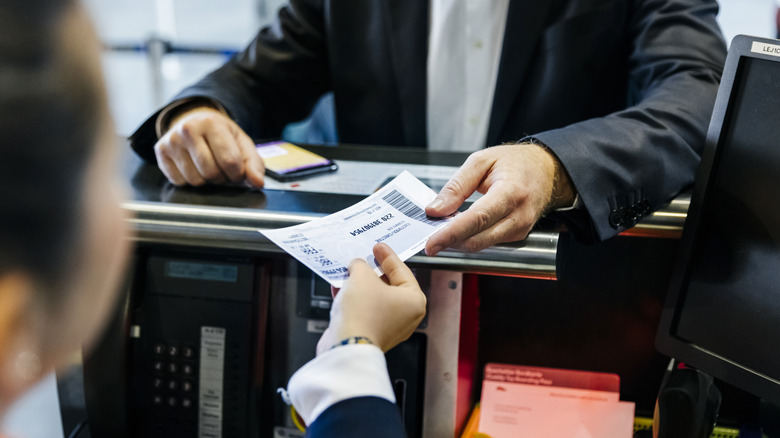 Passenger receiving boarding pass from airline worker